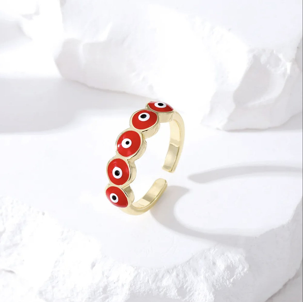 Zara Ring showcasing chunky jewelry with a vibrant evil eye design in gold and enamel on a stone surface.